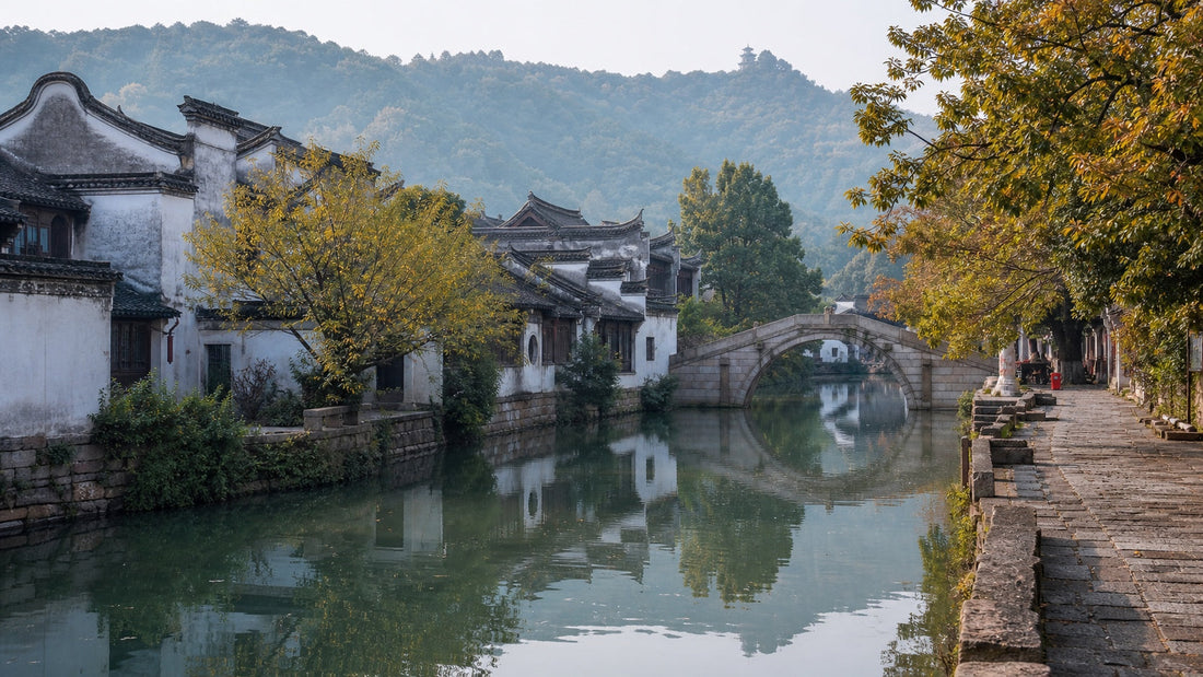 Traditional white-walled houses and a stone arch bridge reflected in the river at Huishan Ancient Town, Wuxi