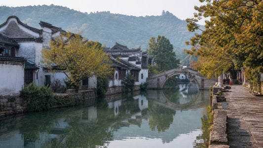 Traditional white-walled houses and a stone arch bridge reflected in the river at Huishan Ancient Town, Wuxi