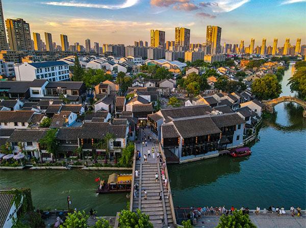 Aerial view of historic riverside homes, canals and the modern skyline in the Qingming Bridge block of Wuxi.